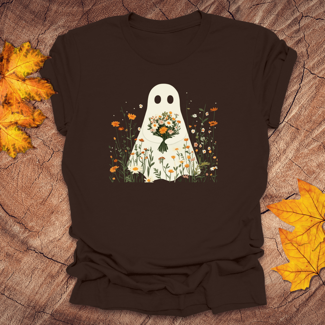 Black t-shirt with a ghost holding flowers design on a wooden surface with autumn leaves.
