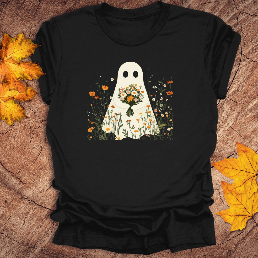 Black t-shirt with a ghost holding flowers design on a wooden surface with autumn leaves.