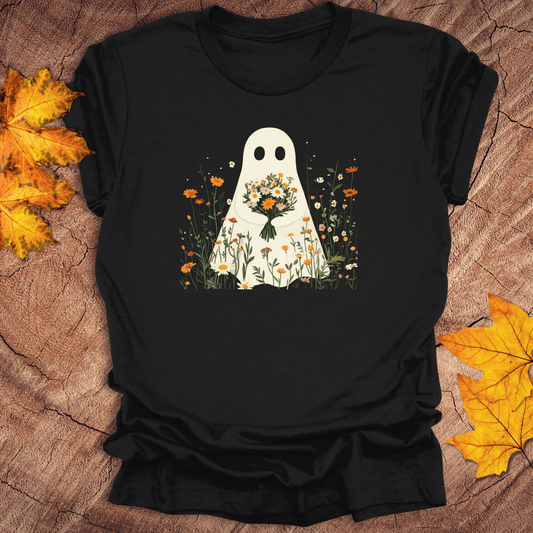 Black t-shirt with a ghost holding flowers design on a wooden surface with autumn leaves.