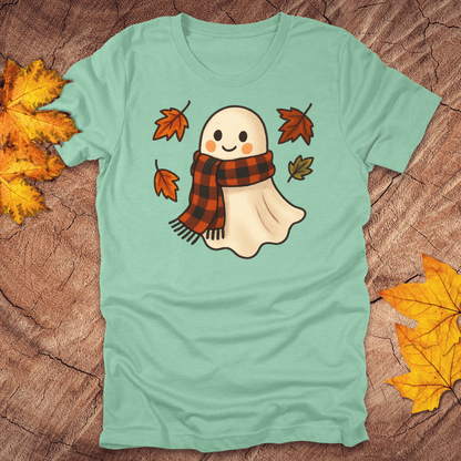 mint green t-shirt with a ghost wearing a plaid scarf design on a wooden surface with autumn leaves.