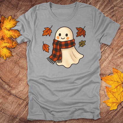 Gray t-shirt with a ghost wearing a plaid scarf design on a wooden surface with autumn leaves.