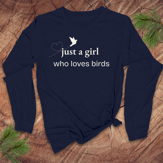 Navy blue long-sleeve t-shirt with 'just a girl who loves birds' text on a wooden surface with pine branches.