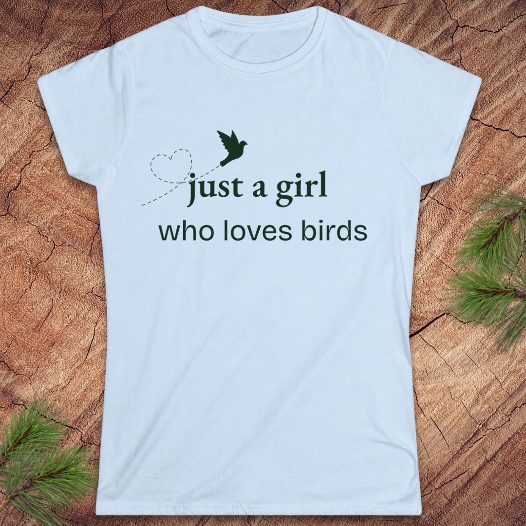 Light blue t-shirt with a bird and text, 'just a girl who loves birds' on a wood background.