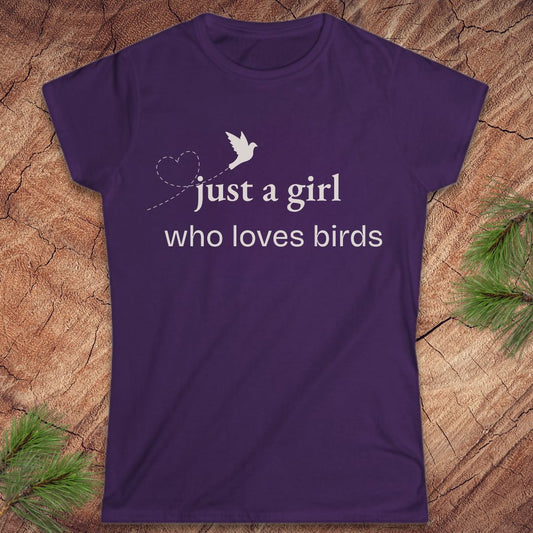 Purple t-shirt with a bird and text, 'just a girl who loves birds' on a wood background.