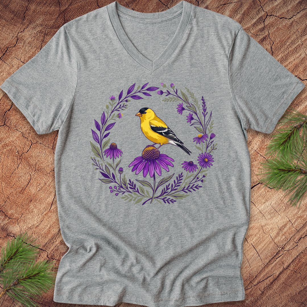 Gray t-shirt with a goldfinch and floral design on a wooden surface