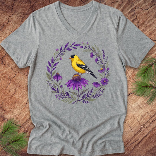 Gray t-shirt with a goldfinch and floral design on a wooden surface