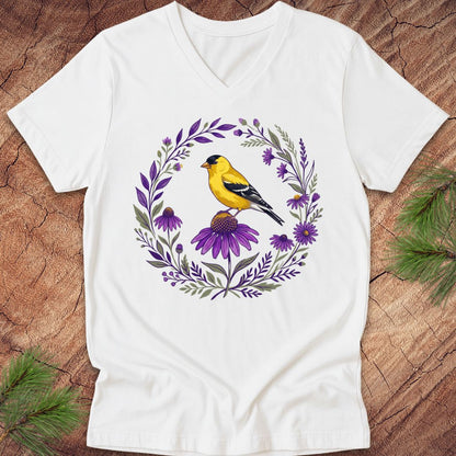 White t-shirt with a goldfinch bird and purple floral design on a wooden surface