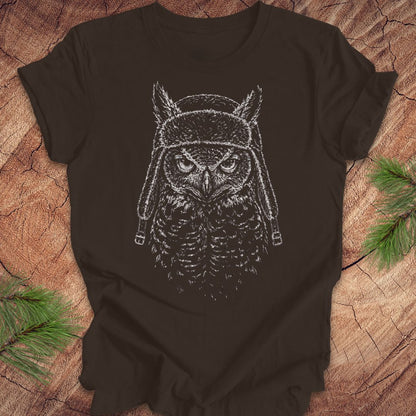Brown t-shirt with an owl graphic wearing a helmet on a wooden surface.