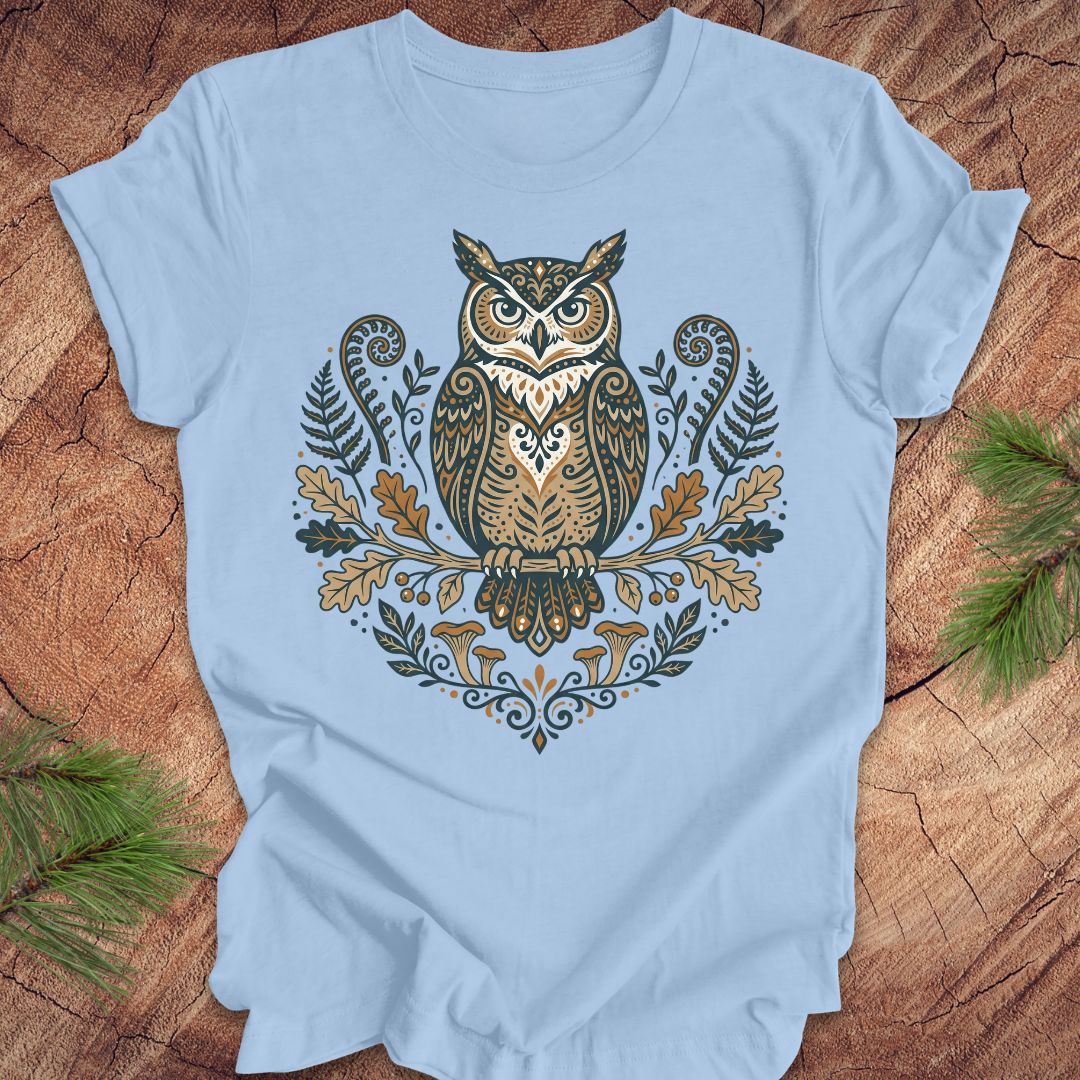 Light blue t-shirt with an owl and woodland design on a wooden surface