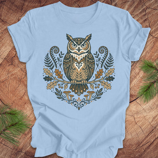 Light blue t-shirt with an owl and woodland design on a wooden surface