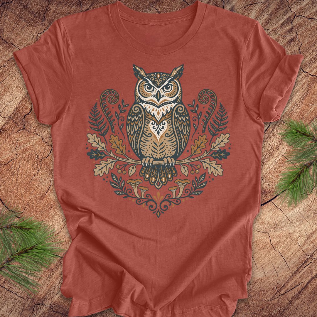 Clay colored t-shirt with an owl and woodland design on a wooden surface