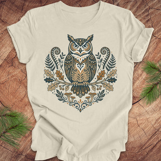 Beige t-shirt with an owl and woodland design on a wooden surface
