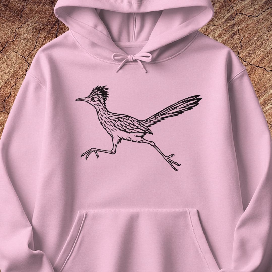 A light pink pullover hoodie with a black line art illustration of a running roadrunner bird on the chest, displayed flat against a textured wood background.