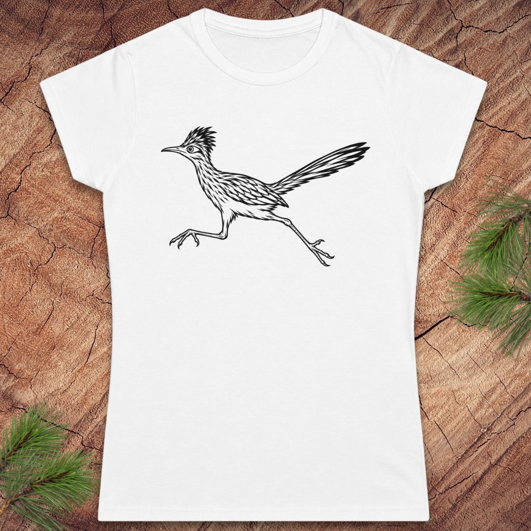 A white short-sleeve crewneck t-shirt featuring a black line art illustration of a running roadrunner bird, displayed flat on a textured brown wood background with pine needles in the corners.