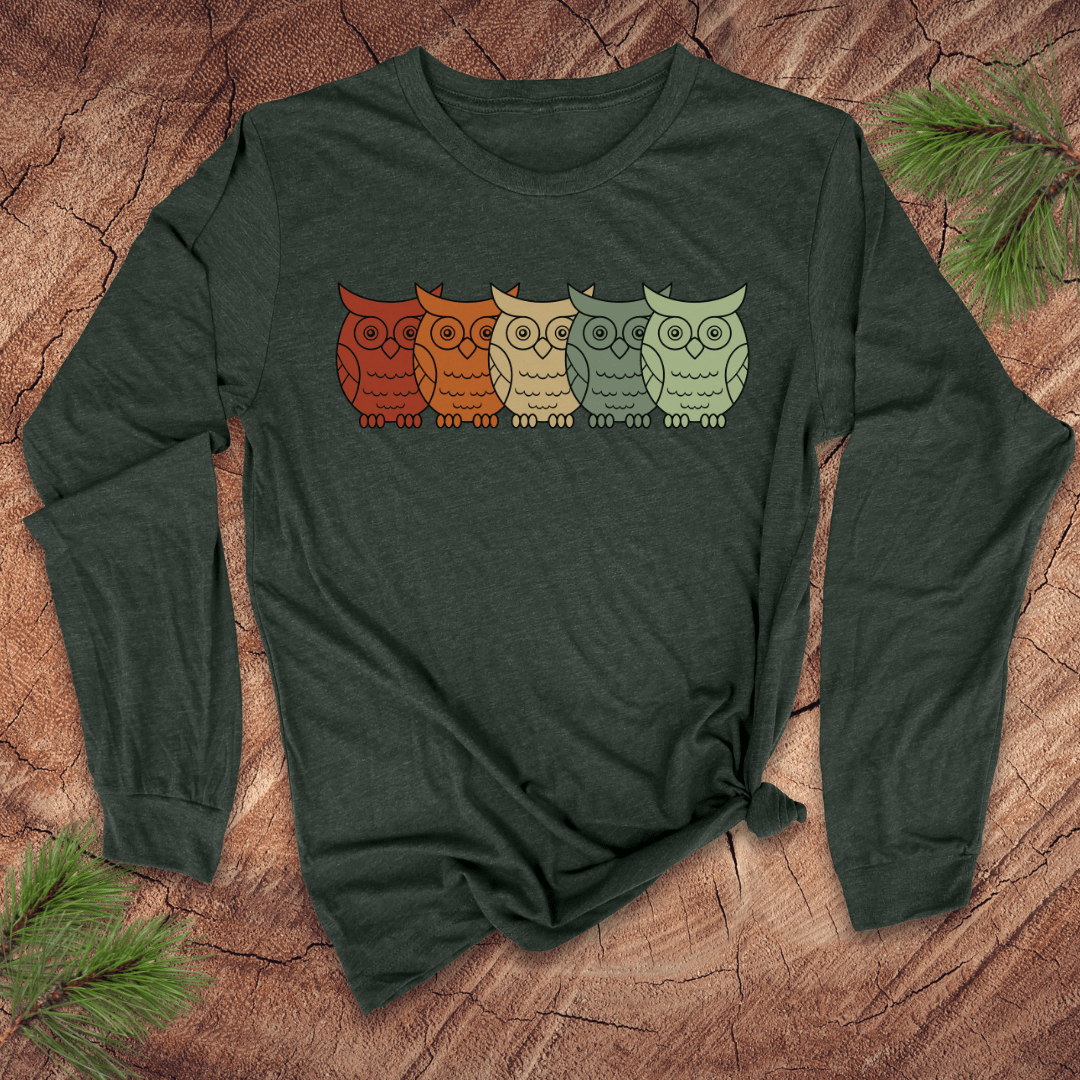 Green long-sleeve shirt with colorful owl design on a wooden surface