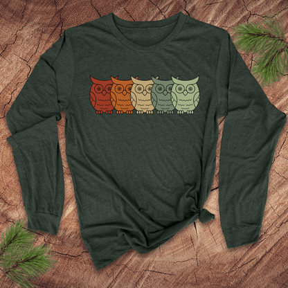 Green long-sleeve shirt with colorful owl design on a wooden surface