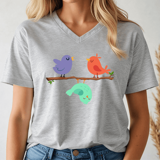 Person wearing a gray v-neck t-shirt with colorful birds on a branch design.