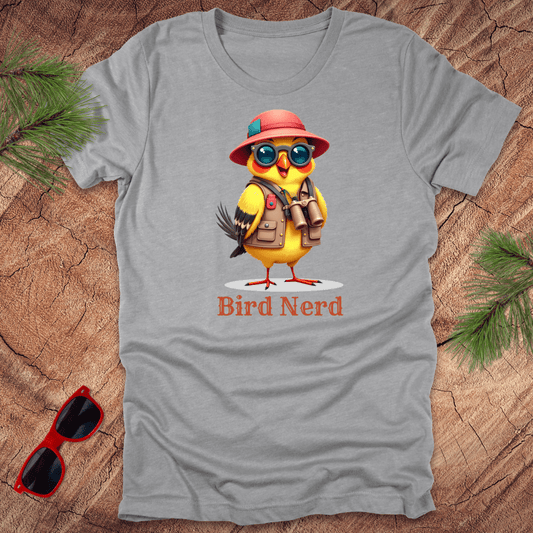 Grey t-shirt with an animated goldfinch in birdwatcher gear and text, 'Bird nerd' on a wood background.