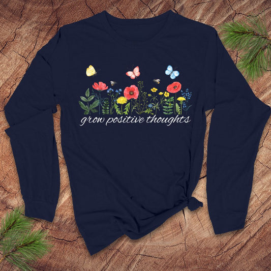 Navy blue long-sleeve shirt with floral design and "grow positive thoughts' text on a wooden surface