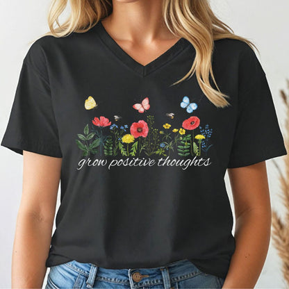 Black v-neck t-shirt with floral design and 'grow positive thoughts' text worn by a person.