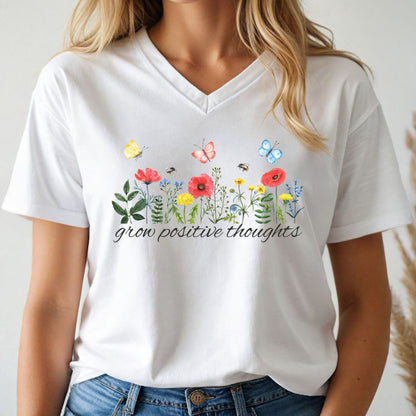 White v-neck t-shirt with floral design and 'grow positive thoughts' text worn by a person.