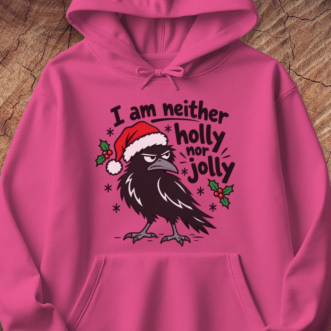 Heliconia pink hoodie with a grumpy raven in a Santa hat surrounded by holly and snowflakes and the words I am neither holly nor jolly, laid flat on a rustic wood background.