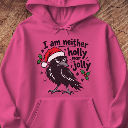 Heliconia pink hoodie with a grumpy raven in a Santa hat surrounded by holly and snowflakes and the words I am neither holly nor jolly, laid flat on a rustic wood background.
