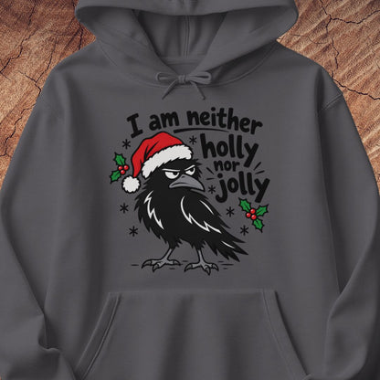 Charcoal gray hoodie with a grumpy raven in a Santa hat surrounded by holly and snowflakes and the words I am neither holly nor jolly, laid flat on a rustic wood background.