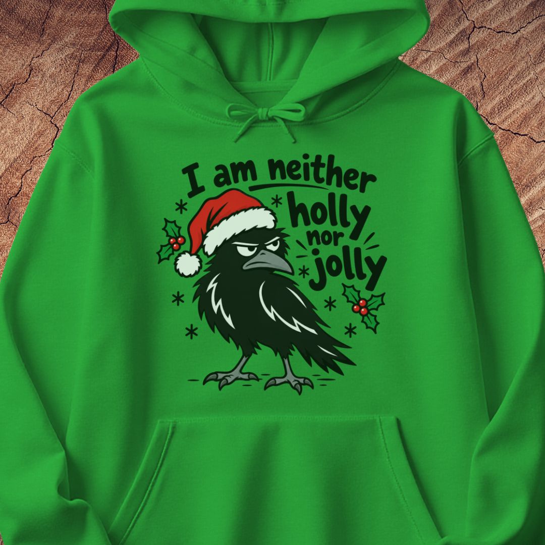 Irish green hoodie with a grumpy raven in a Santa hat surrounded by holly and snowflakes and the words I am neither holly nor jolly, laid flat on a rustic wood background.
