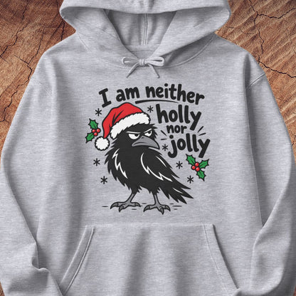Sport grey hoodie with a grumpy raven in a Santa hat surrounded by holly and snowflakes and the words I am neither holly nor jolly, laid flat on a rustic wood background.