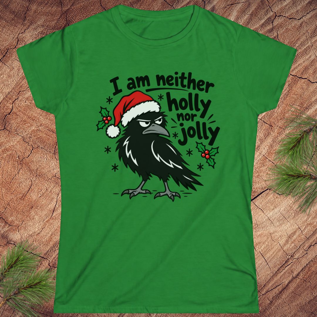 Irish green women's t-shirt with a grumpy raven in a Santa hat surrounded by holly and snowflakes and the words I am neither holly nor jolly, laid flat on a rustic wood background with pine branches.