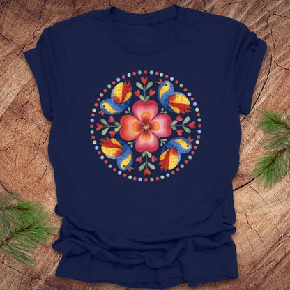 Navy blue t-shirt with a colorful floral and bird design on a wooden surface.