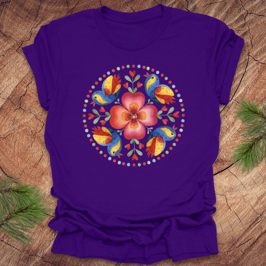 Purple t-shirt with a colorful floral and bird design on a wooden surface
