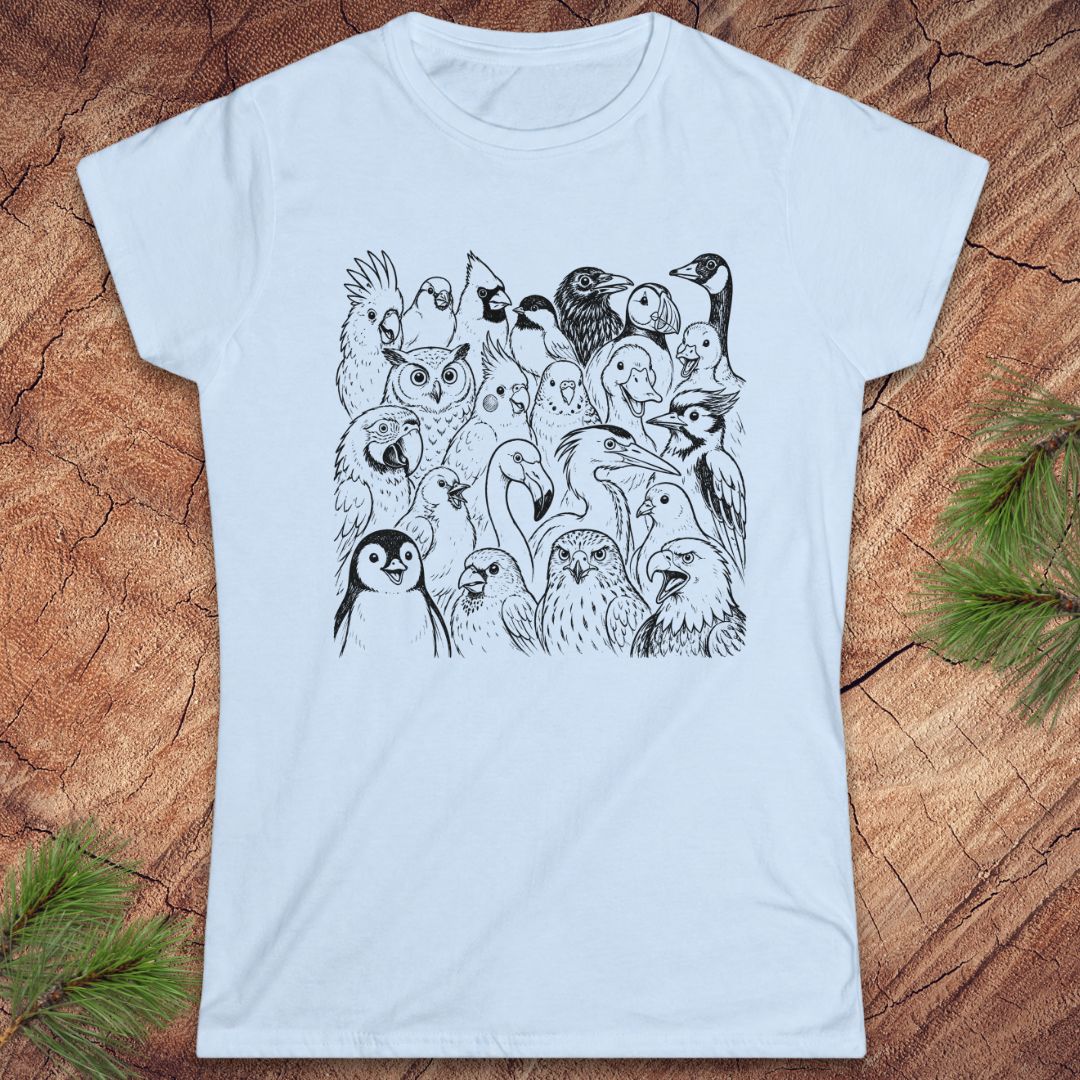 A light blue short-sleeve crewneck t-shirt featuring a black line art graphic of a dense group of various birds, laid flat on a textured wood background with pine needles in the corners.