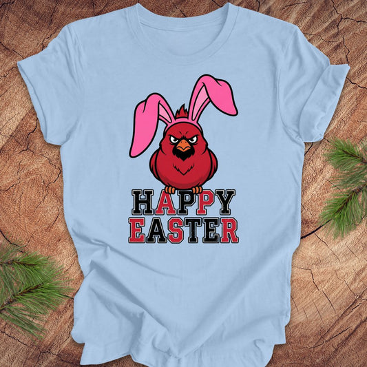 Light blue t-shirt with a cardinal wearing bunny ears and 'Happy Easter' text on a wooden surface.
