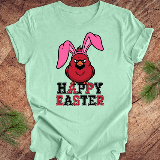 Mint green t-shirt with a cardinal wearing bunny ears and 'Happy Easter' text on a wooden surface.