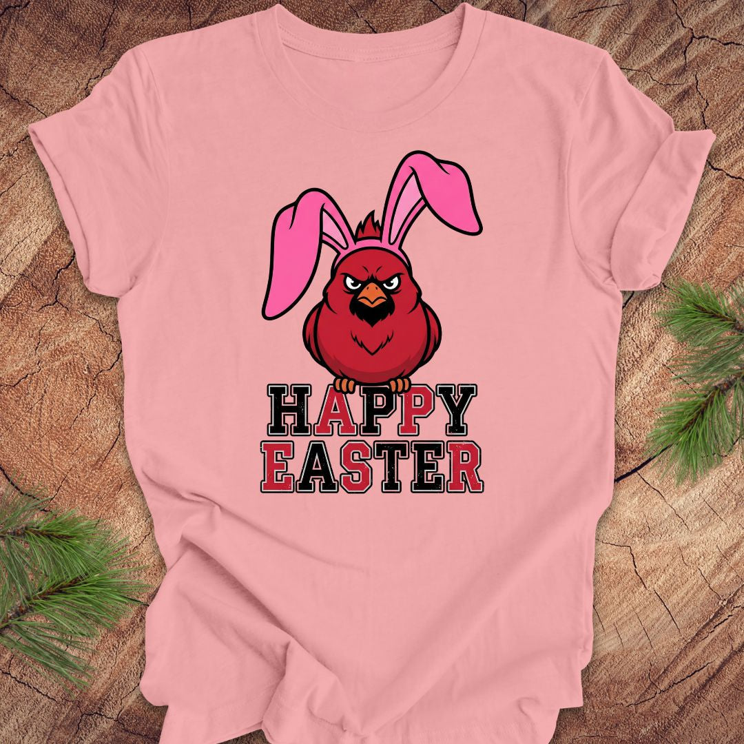 Pink t-shirt with a cardinal wearing bunny ears and 'Happy Easter' text on a wooden surface.