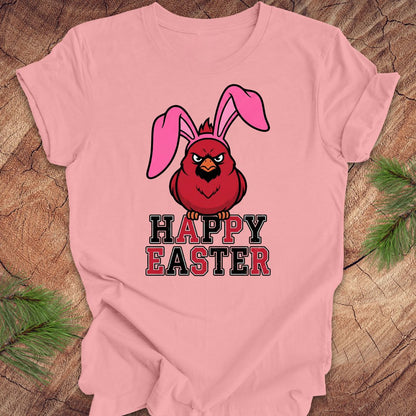 Pink t-shirt with a cardinal wearing bunny ears and 'Happy Easter' text on a wooden surface.