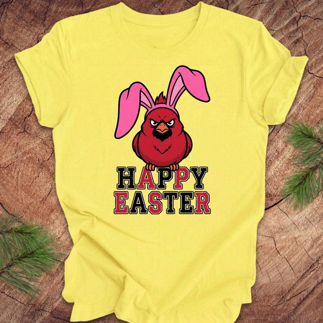 Yellow t-shirt with a cardinal wearing bunny ears and 'Happy Easter' text on a wooden surface.