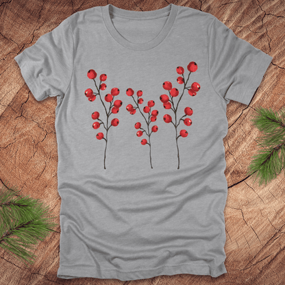 Grey t-shirt with three tall holly berry branches on a wood background with pine branches.