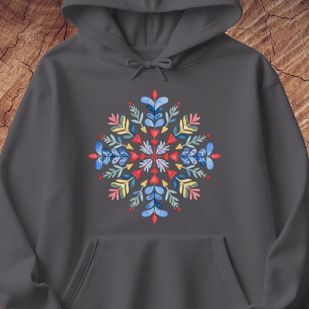 A dark gray pullover hoodie with a colorful, symmetrical snowflake design printed on the chest, set against a rustic wood background.