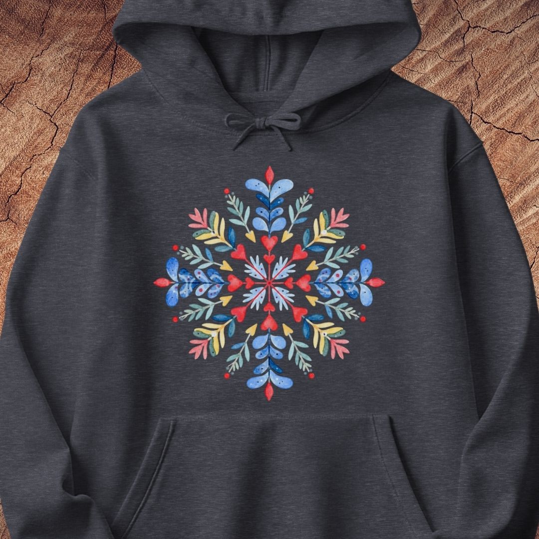 A dark heather gray hoodie featuring a colorful, symmetrical snowflake graphic on the chest, displayed flat against a rustic wood background.