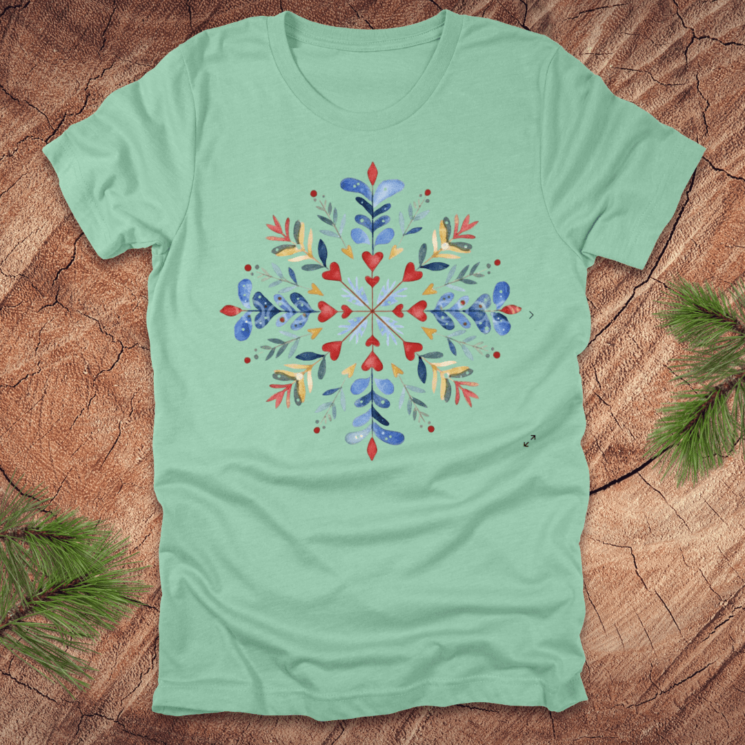 Mint green t-shirt with a colorful snowflake floral design on a wooden surface