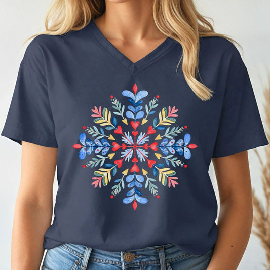 A woman wearing a navy blue V-neck t-shirt with a colorful, symmetrical snowflake graphic printed on the chest. The graphic features blue, red, yellow, and green botanical details.