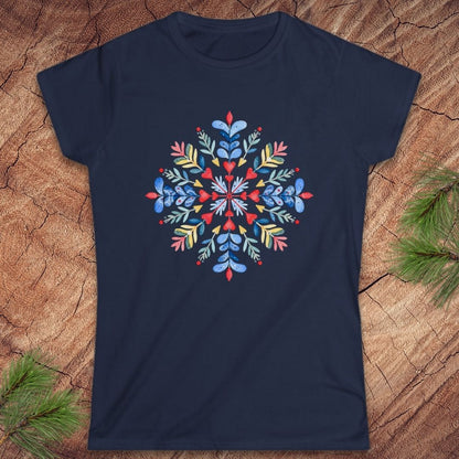 A navy blue short-sleeve crewneck t-shirt featuring a colorful, symmetrical bohemian-style floral mandala print on the chest. The shirt is displayed flat on a textured brown wood background with pine needles in the corners.