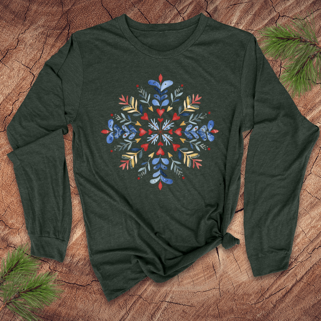 Green long sleeve shirt with a colorful floral snowflake design on a wooden surface.
