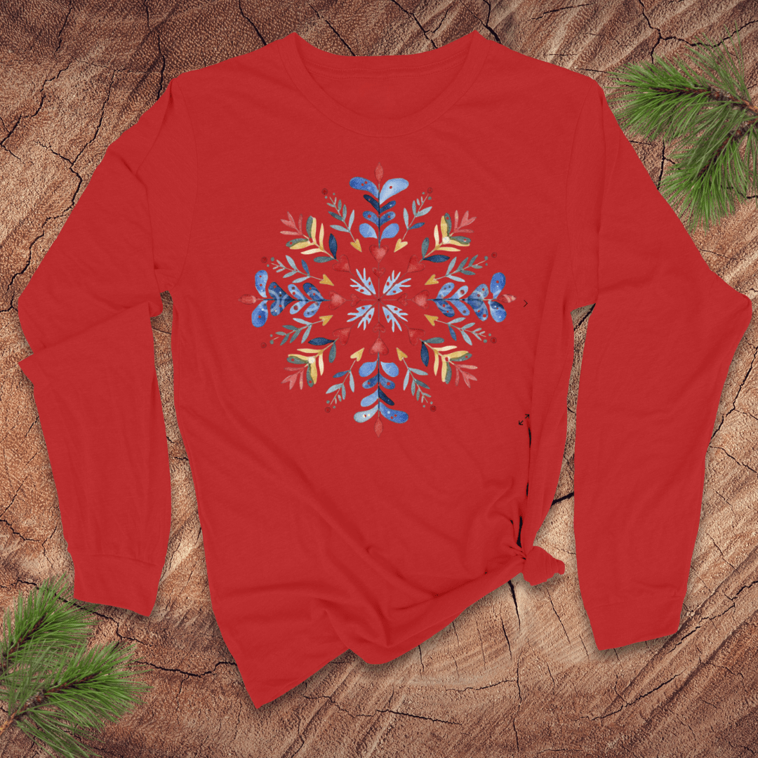 Red long sleeve shirt with a colorful floral snowflake design on a wooden surface.