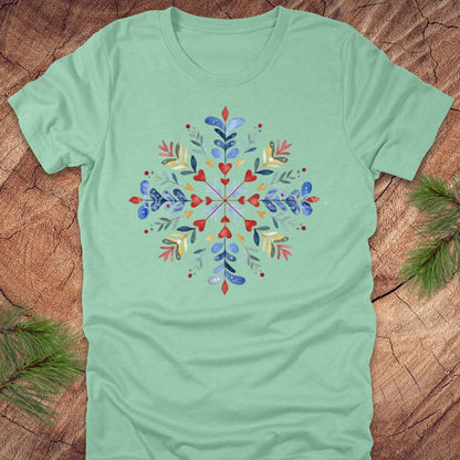 Heather mint t-shirt with a colorful snowflake and floral design on a wooden surface