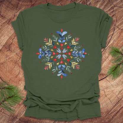 Military green t-shirt with a colorful snowflake and floral design on a wooden surface