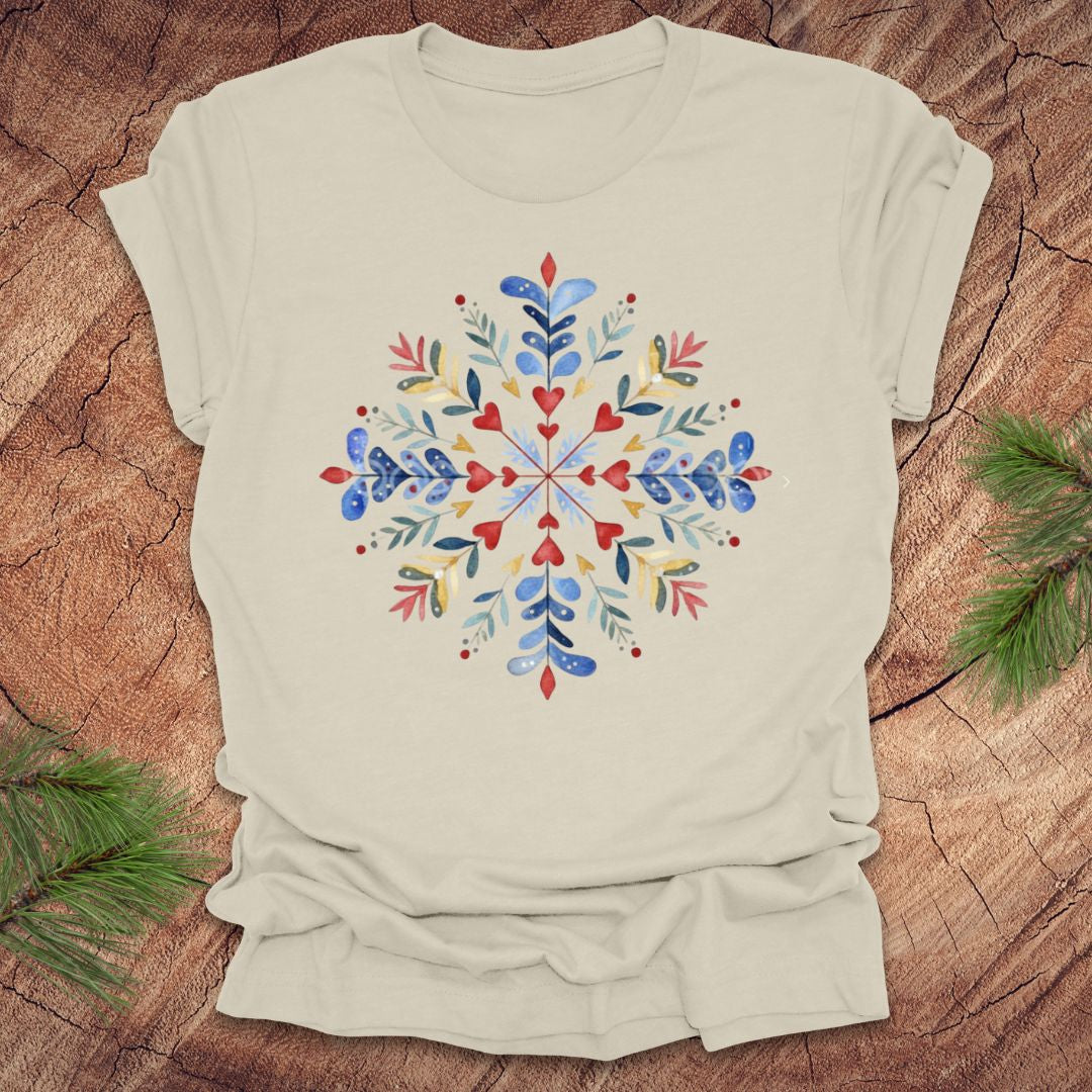 Beige t-shirt with a colorful snowflake and floral design on a wooden surface